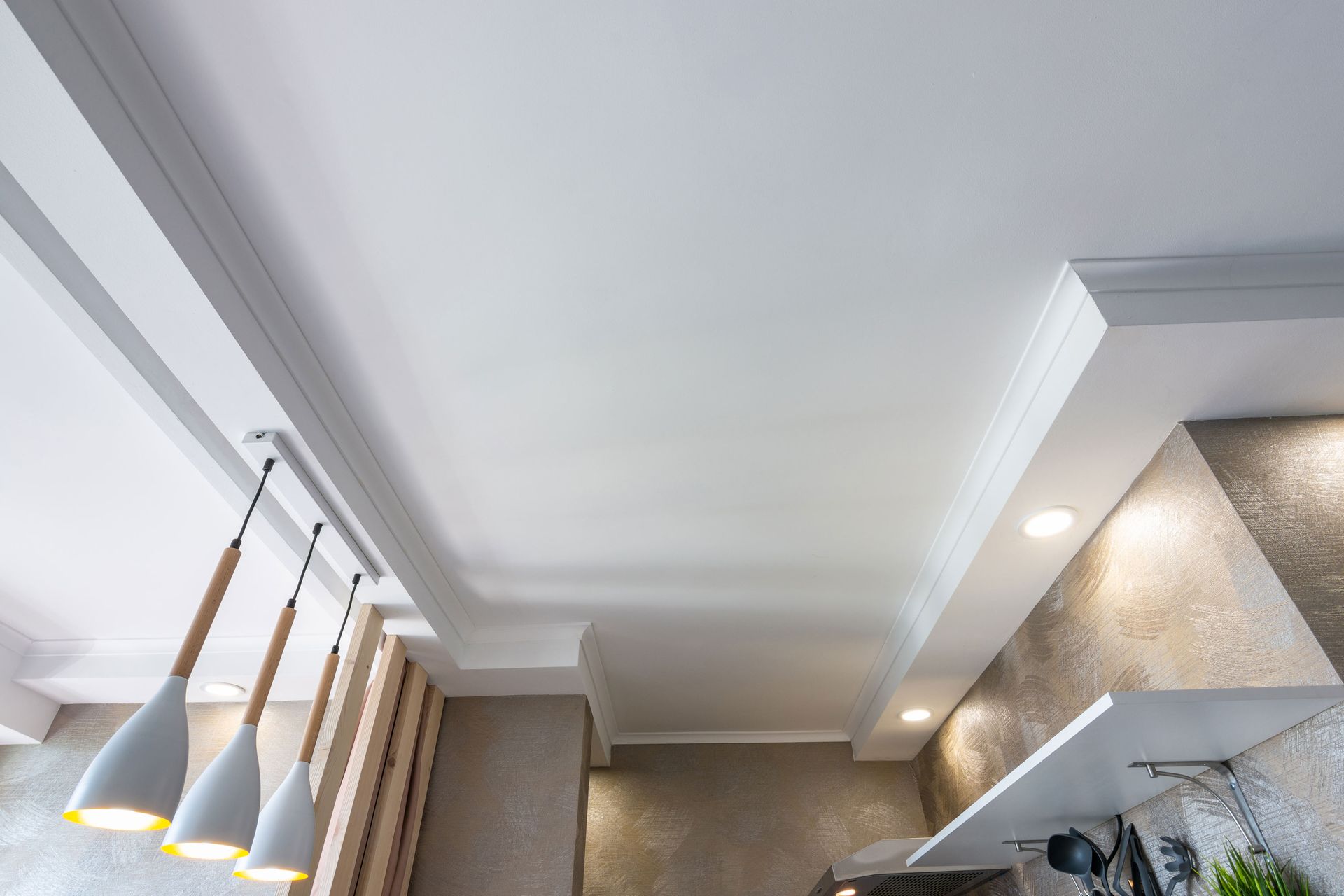 A kitchen with a white ceiling and a few lights hanging from it