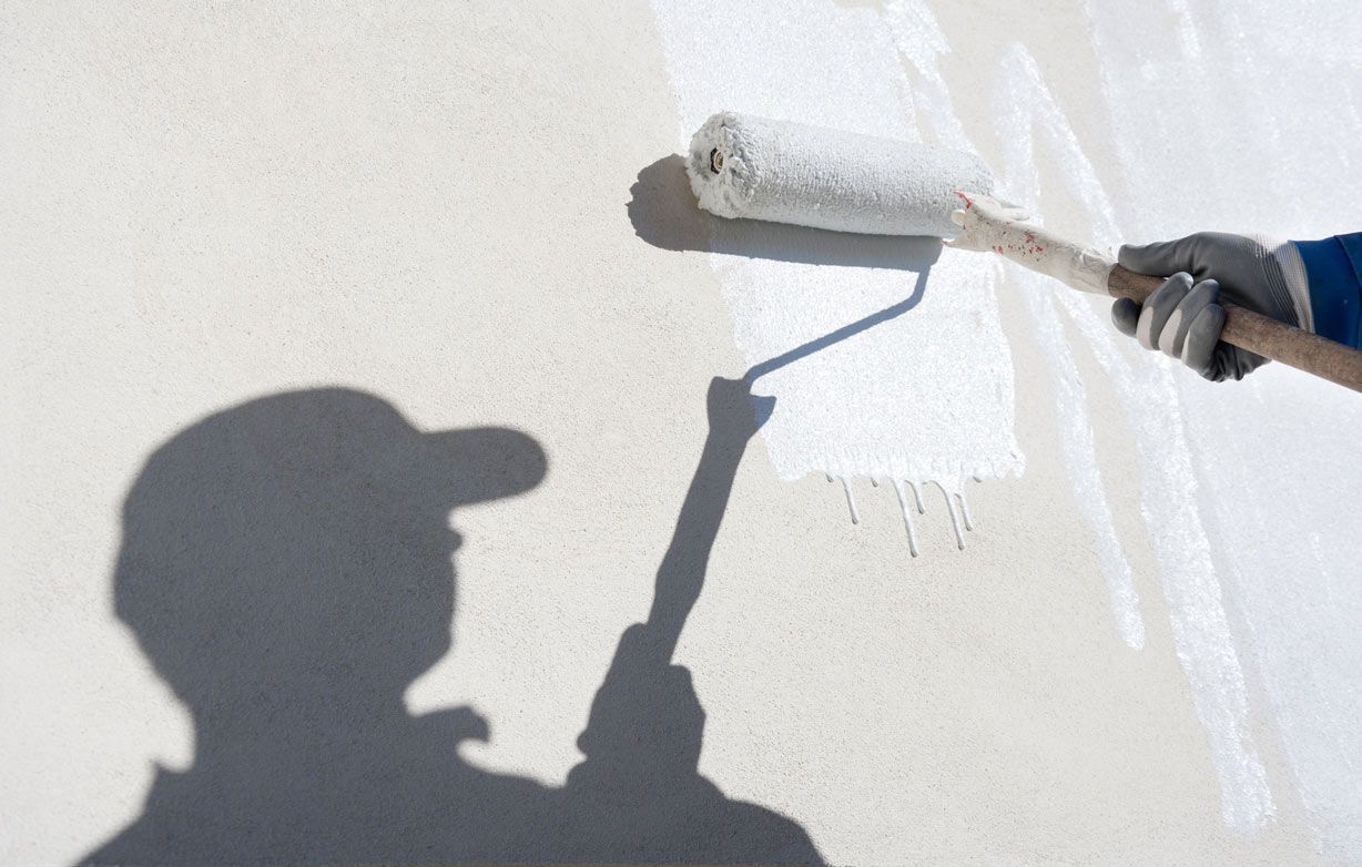 A man is painting a wall with a paint roller