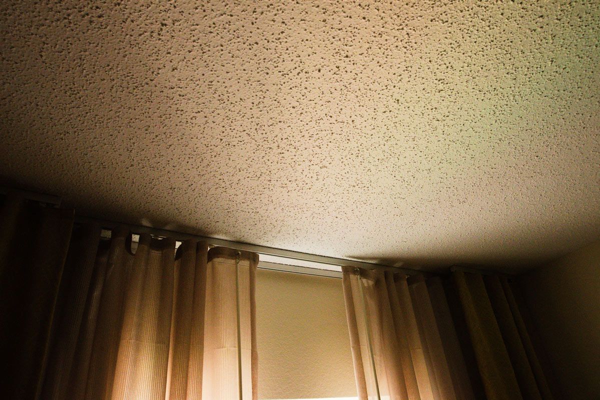 A room with a ceiling and a window with curtains