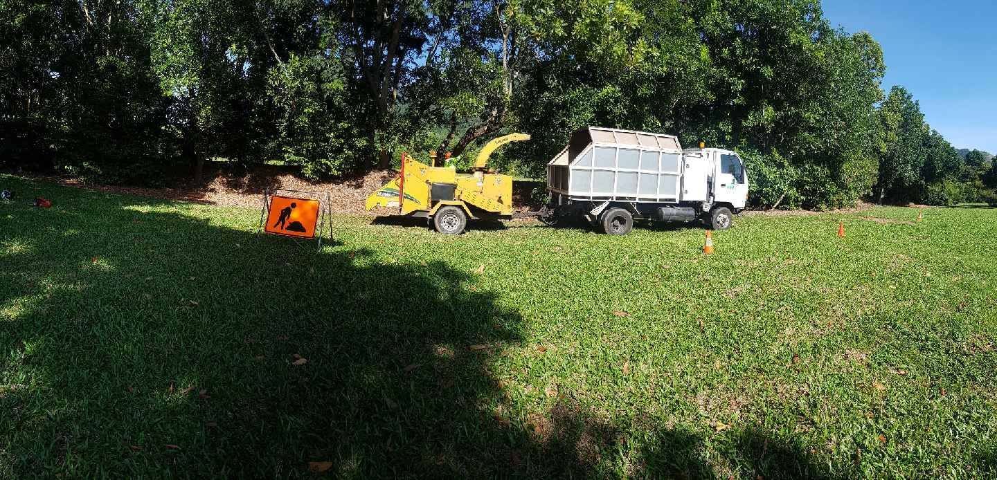 A Truck With A Tree Chipper Attached To It Is Parked In A Grassy Field — Tree Arrangements in Stratford, QLD