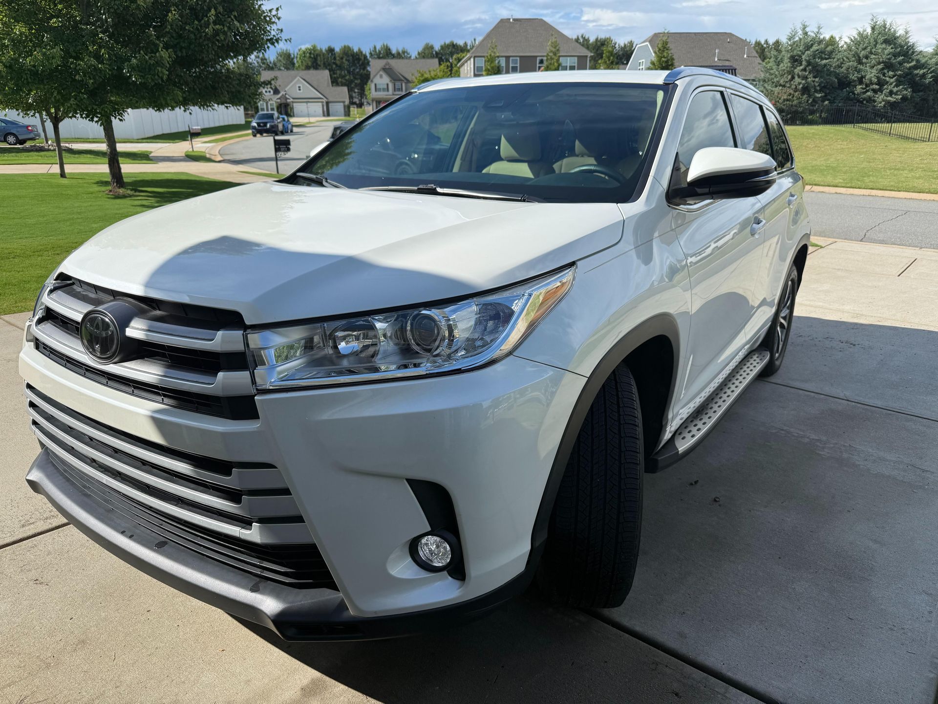 A white toyota highlander is parked in a driveway.