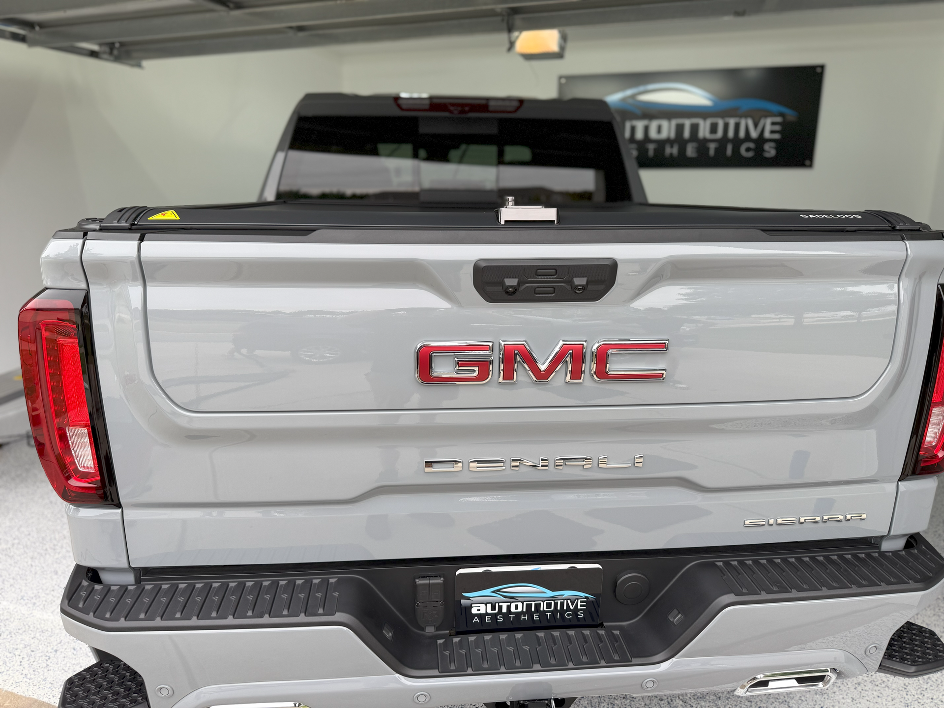 A silver gmc truck is parked in a garage.