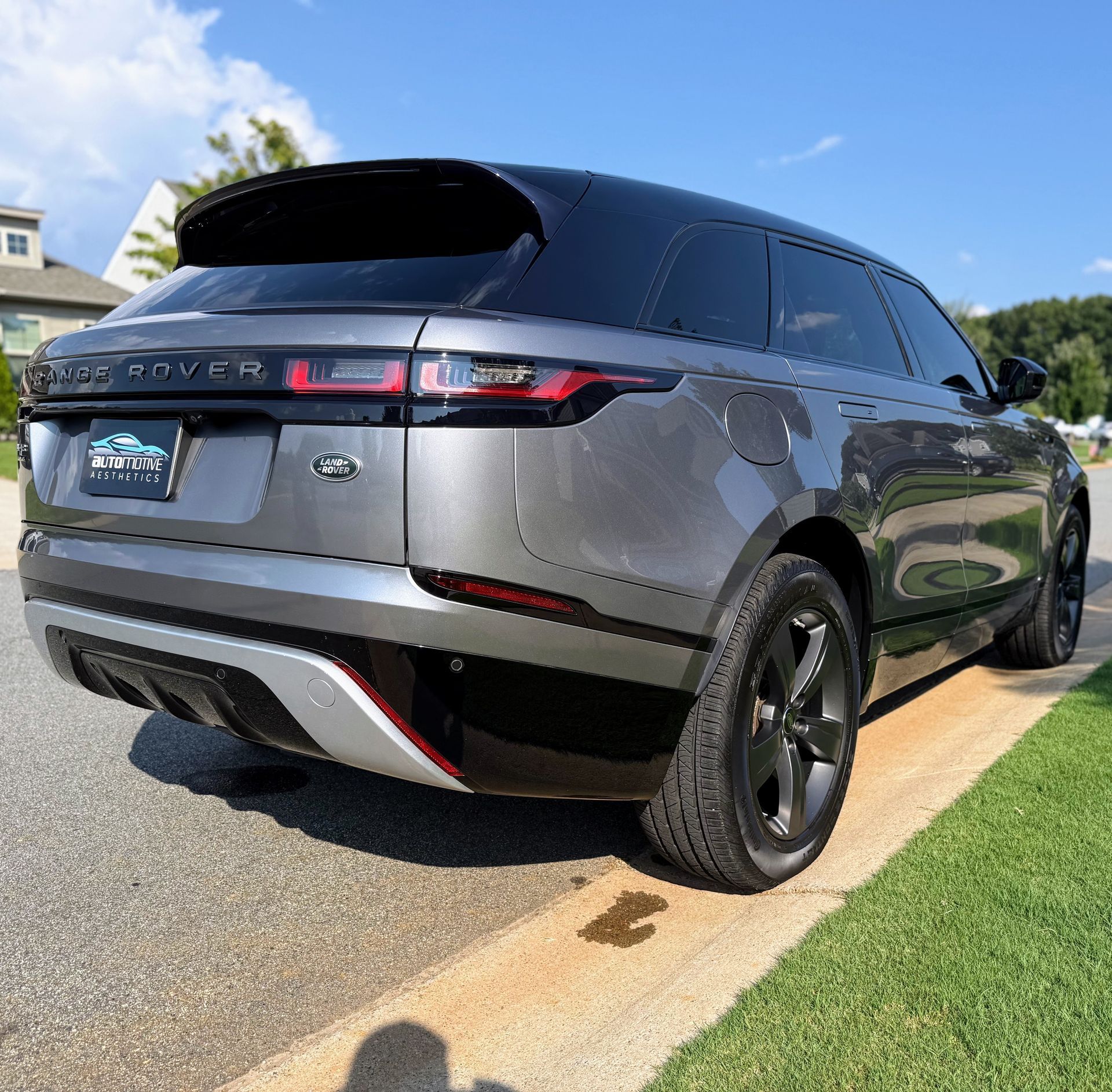 Gray Land Rover SUV parked on a curb, with black accents, sunny outdoor setting.