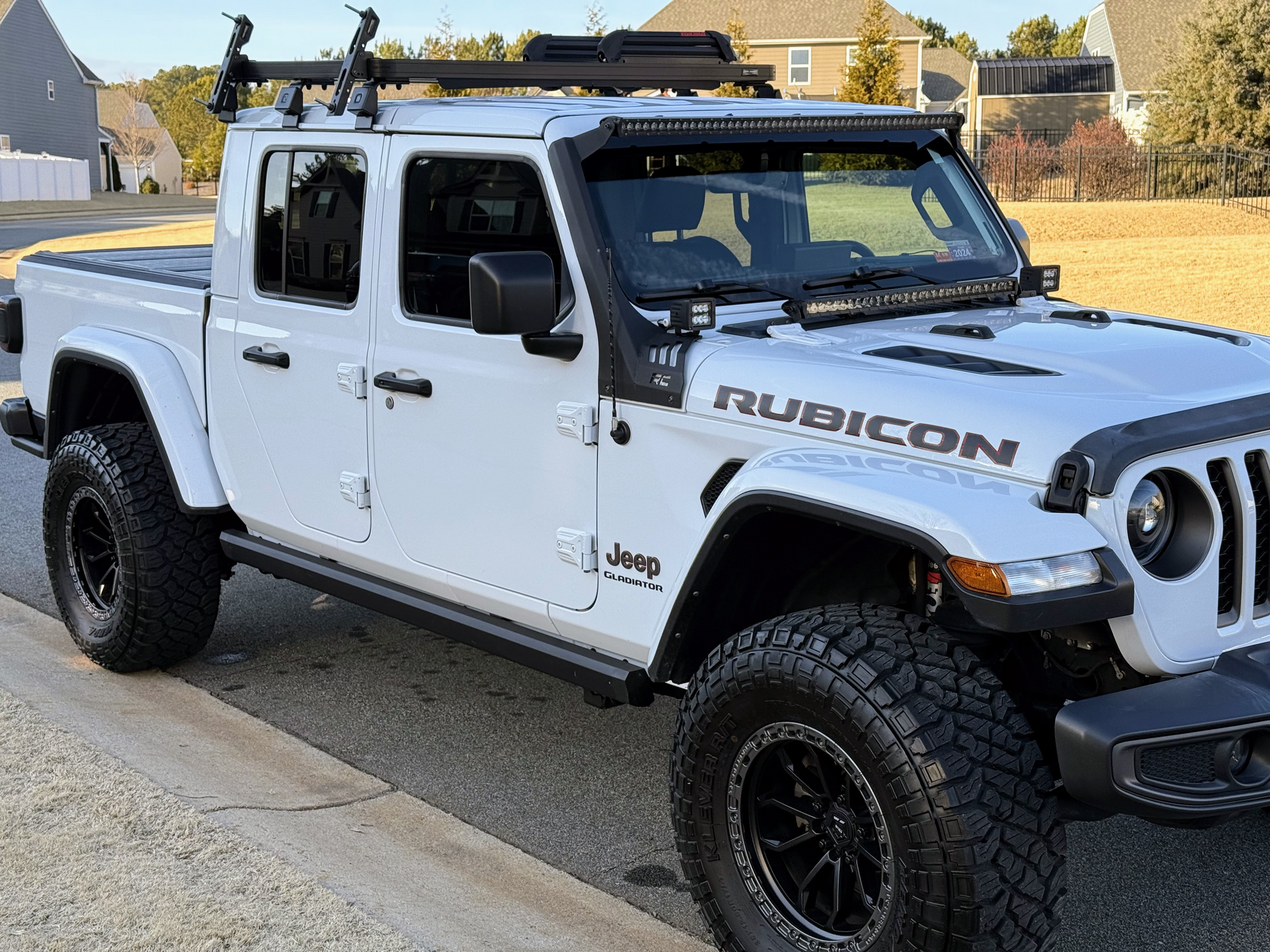A black suv is parked on the side of the road in front of a house.