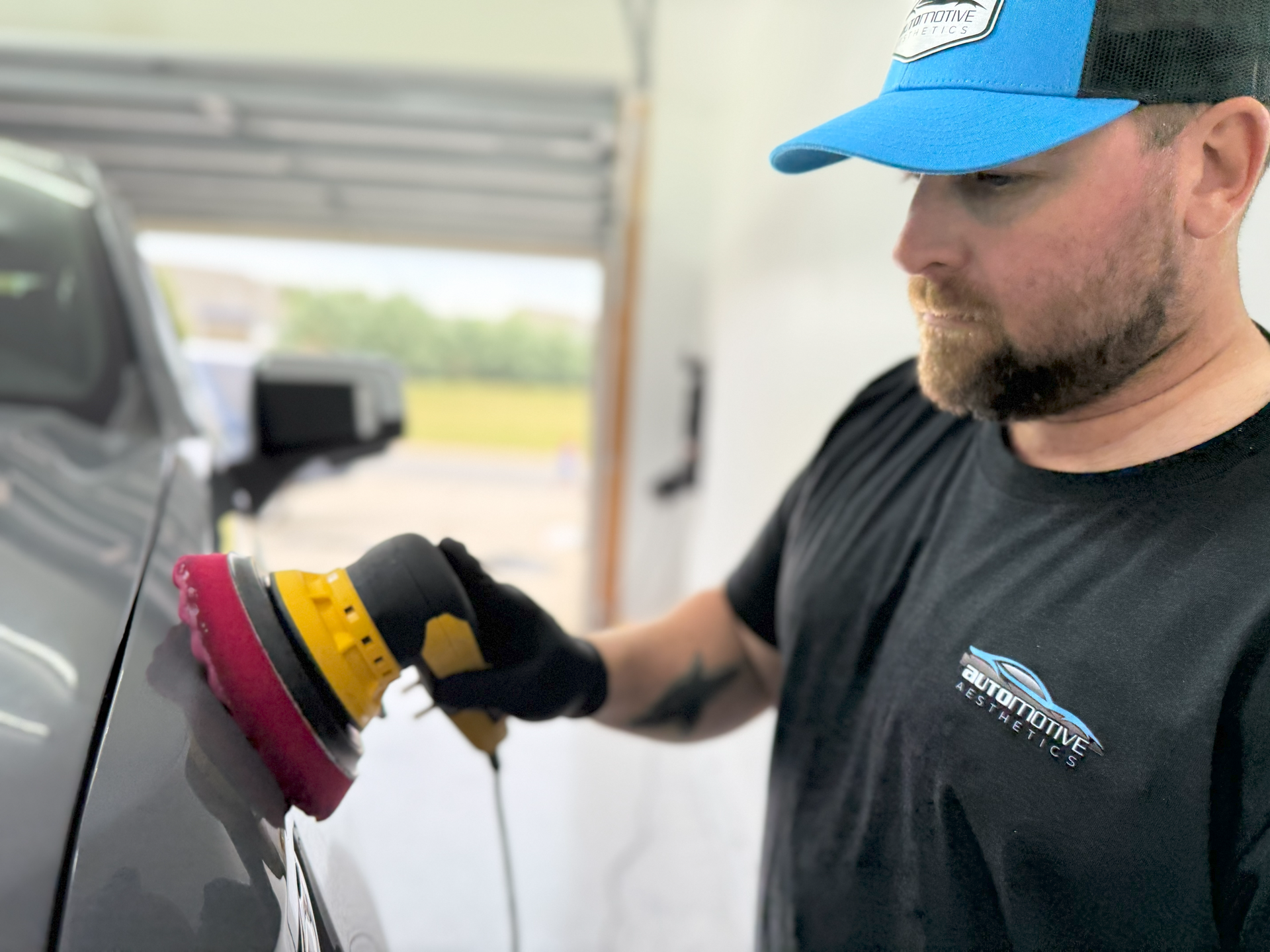 a man is polishing the hood of a car with a machine .