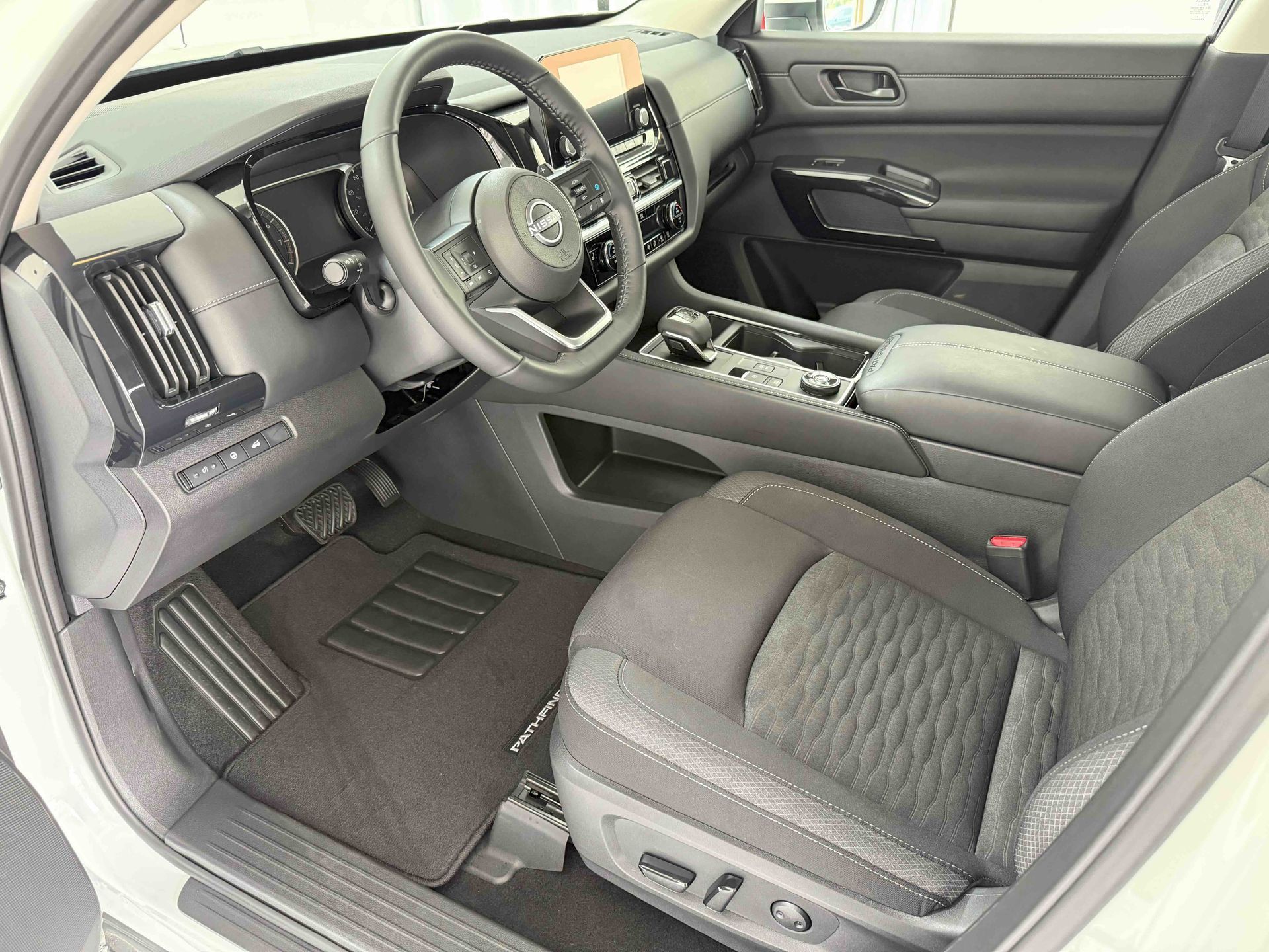 Interior view of a Nissan Pathfinder, showcasing the driver's seat, dashboard, and black fabric seats.