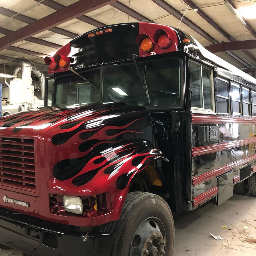 Red and black school bus with flames painted on the front.