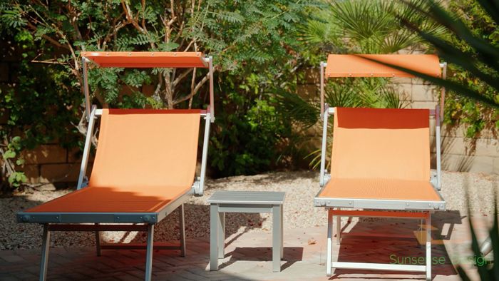 two orange lettini sun loungers side by side with a table inbetween