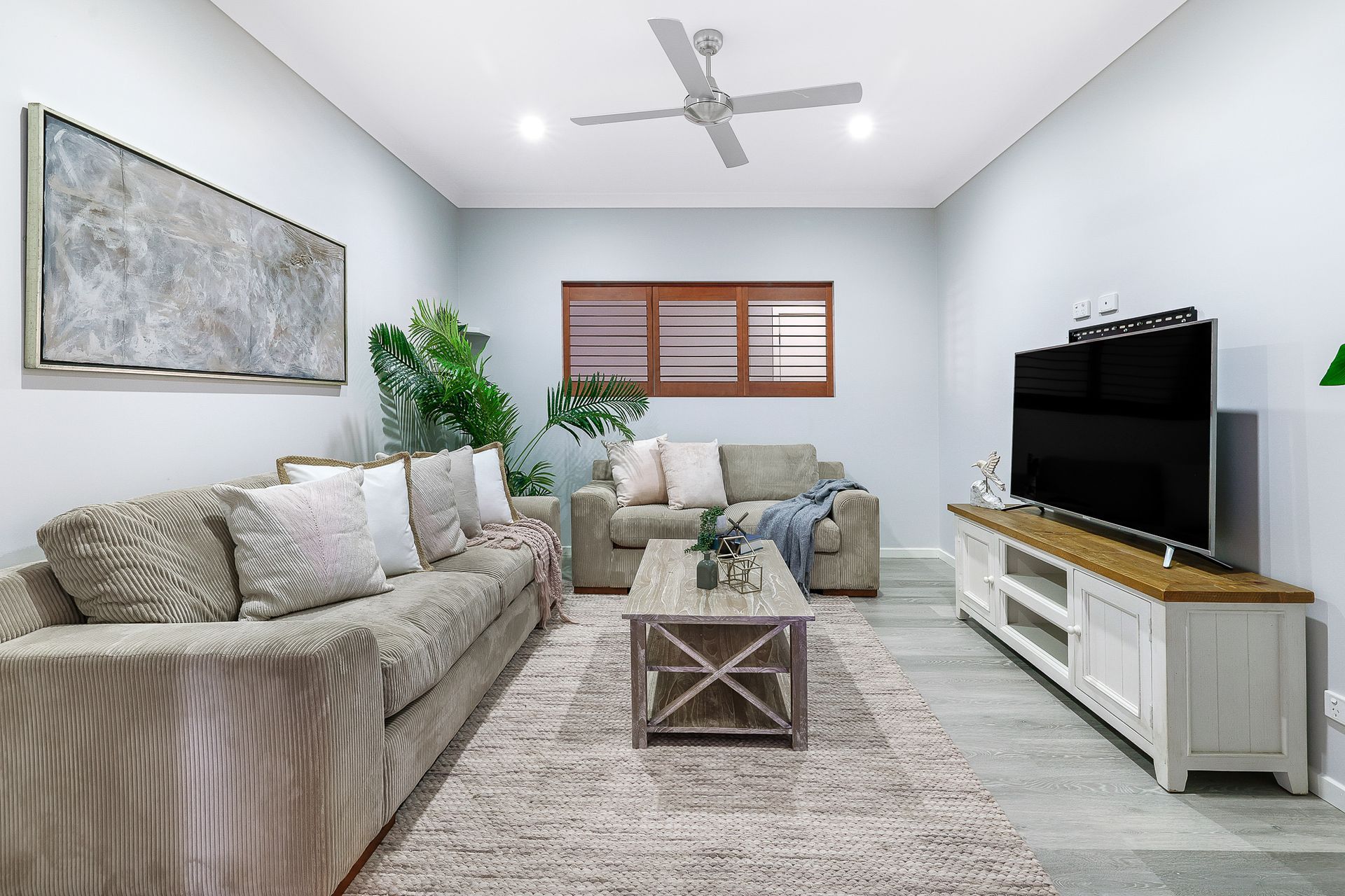 A living room with two couches , a coffee table , and a flat screen tv.