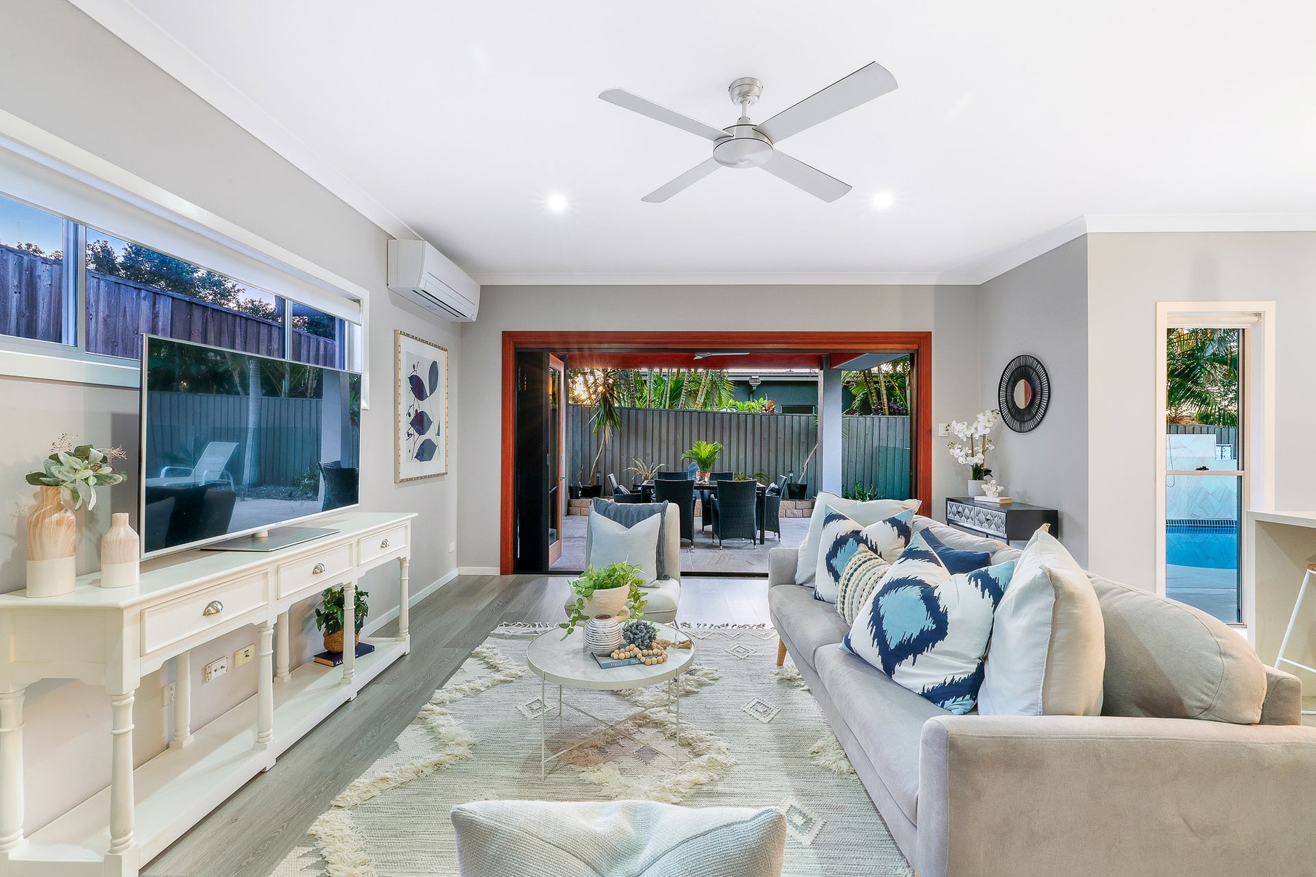 A living room with a couch , television , and ceiling fan.