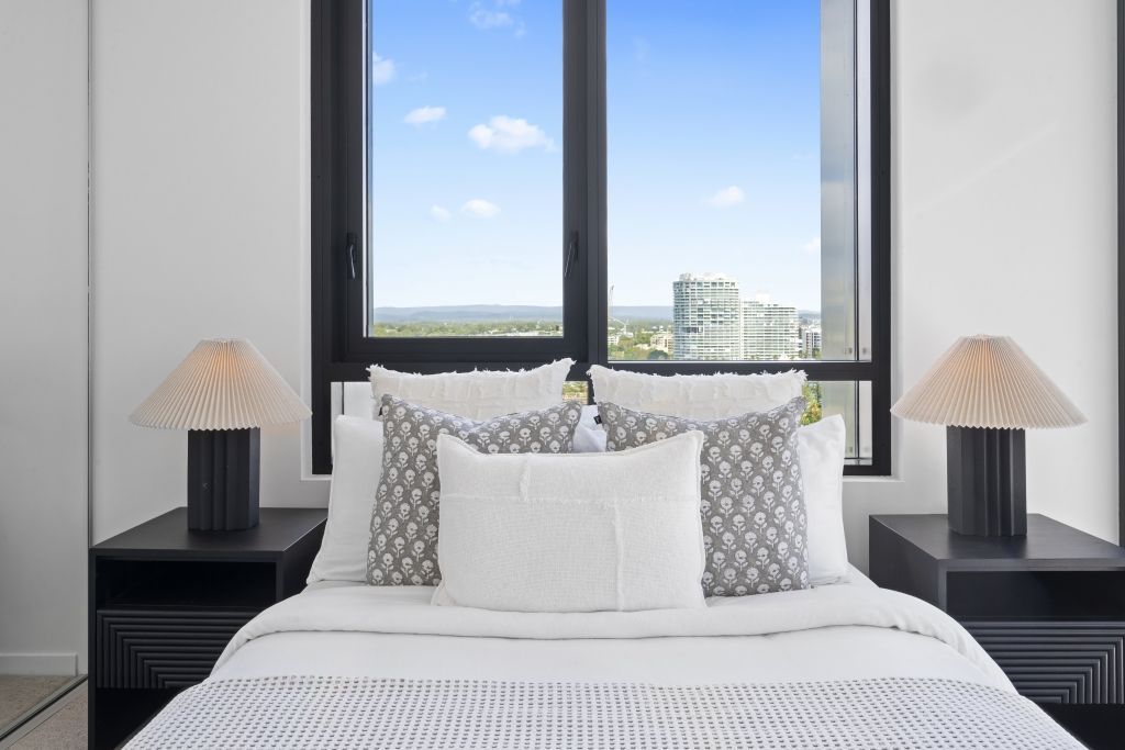 A bedroom with a bed , nightstands , lamps and a window.