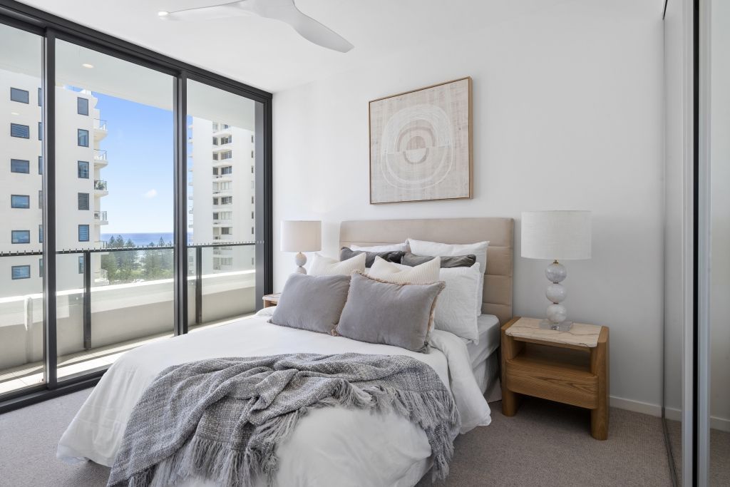 A bedroom with a bed , nightstand , sliding glass doors and a balcony.