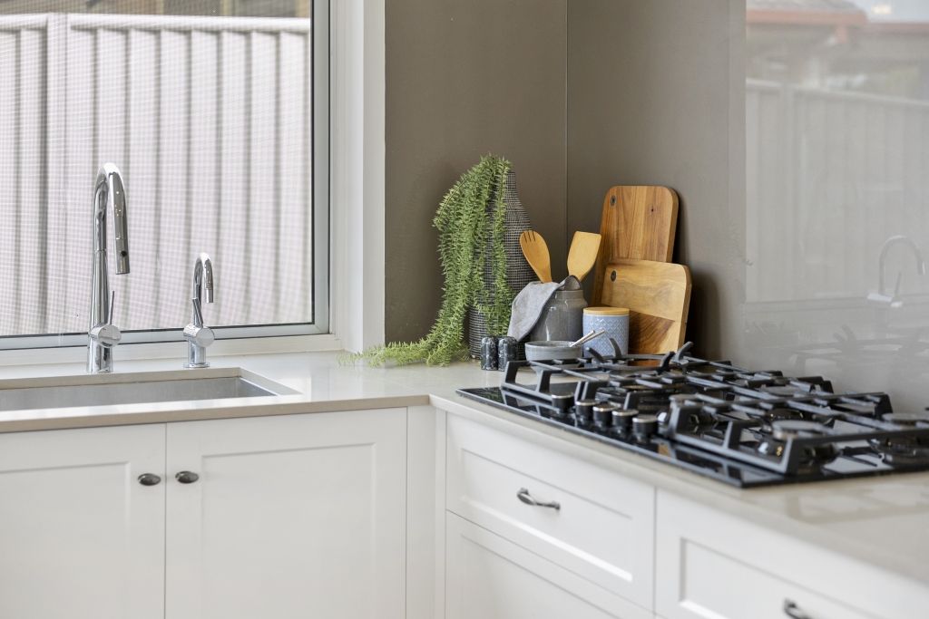 A kitchen with a stove top oven , sink , and window.