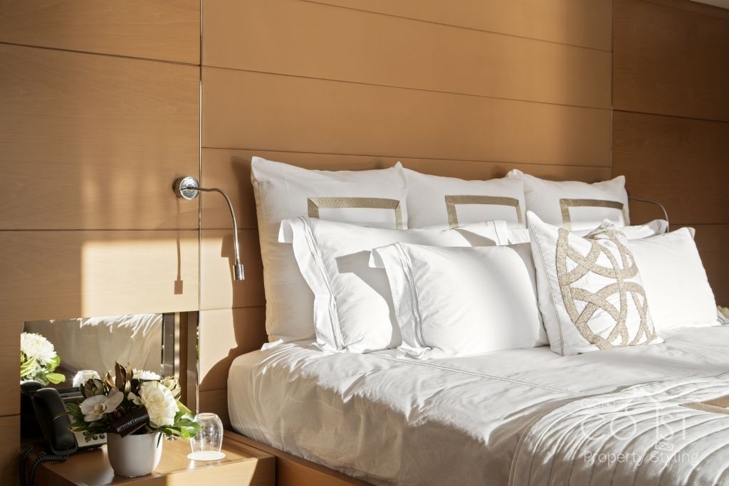 A bed with white sheets and pillows in a bedroom