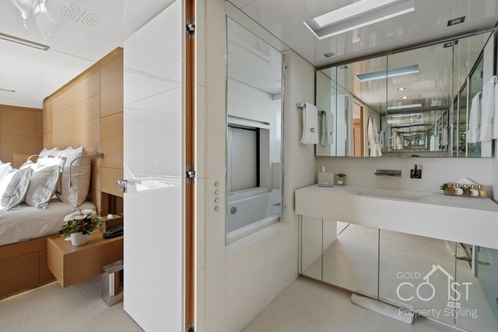 A bathroom with a sink and a mirror next to a bedroom.