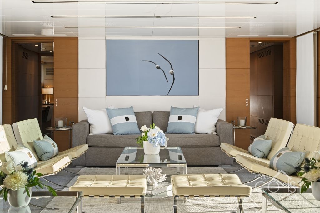 A living room with a couch and chairs and a painting on the wall