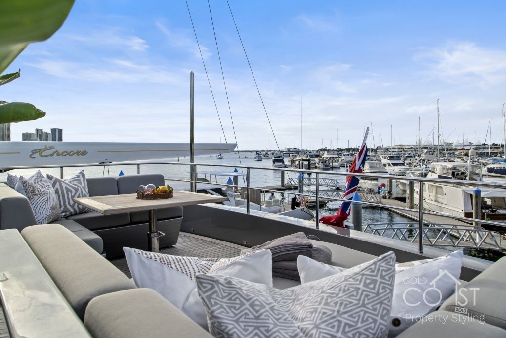 There is a couch and a table on the balcony overlooking the water.