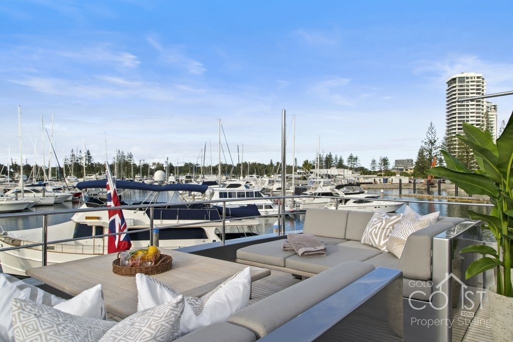 A boat is docked in a marina next to a couch and table.