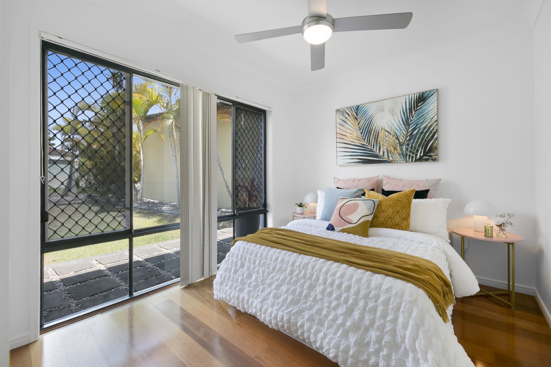 A bedroom with a bed , ceiling fan and sliding glass doors.