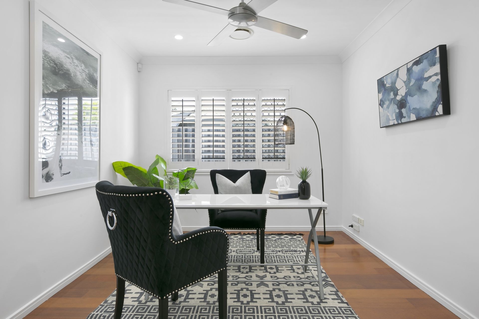 A home office with a desk , chair and ceiling fan.