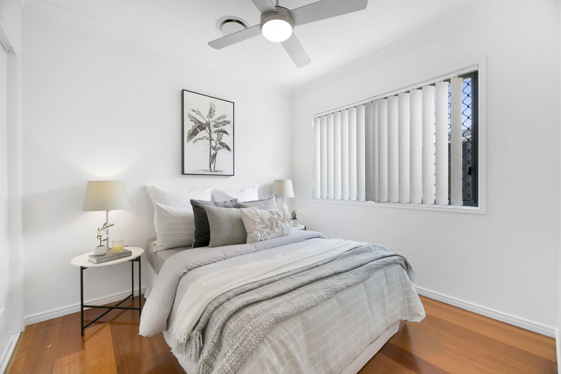 A bedroom with a bed , ceiling fan , lamp and window.