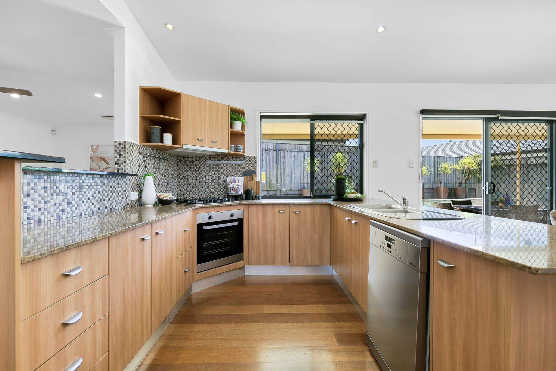 A kitchen with wooden cabinets , granite counter tops , and stainless steel appliances.