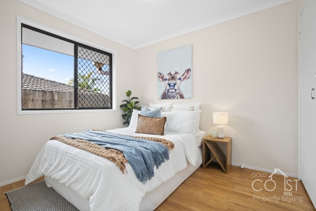 A bedroom with a bed , nightstand , lamp and window.