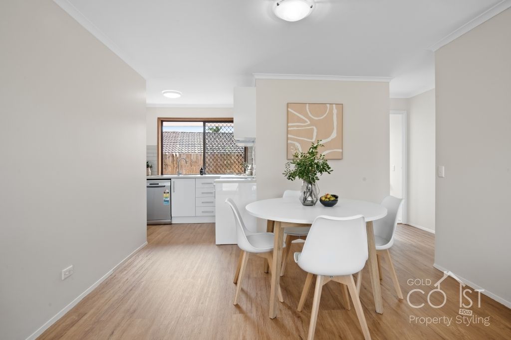 A dining room with a table and chairs and a kitchen in the background.