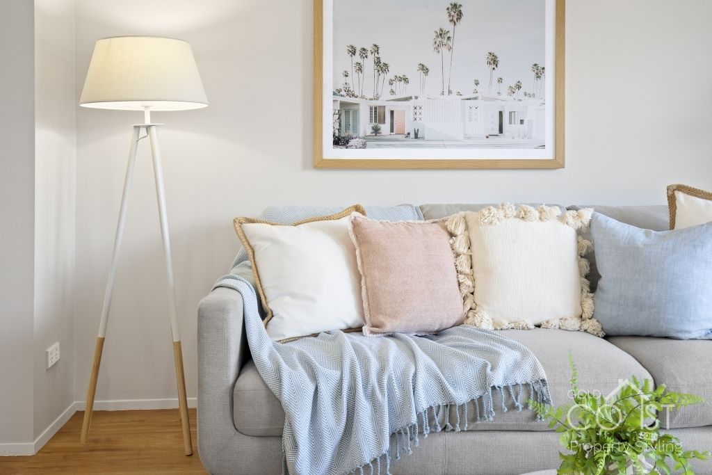 A living room with a couch , lamp , and a picture on the wall.