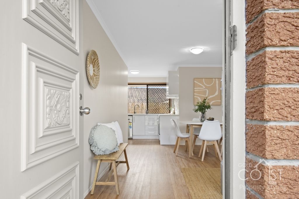 The door is open to a living room with a table and chairs.