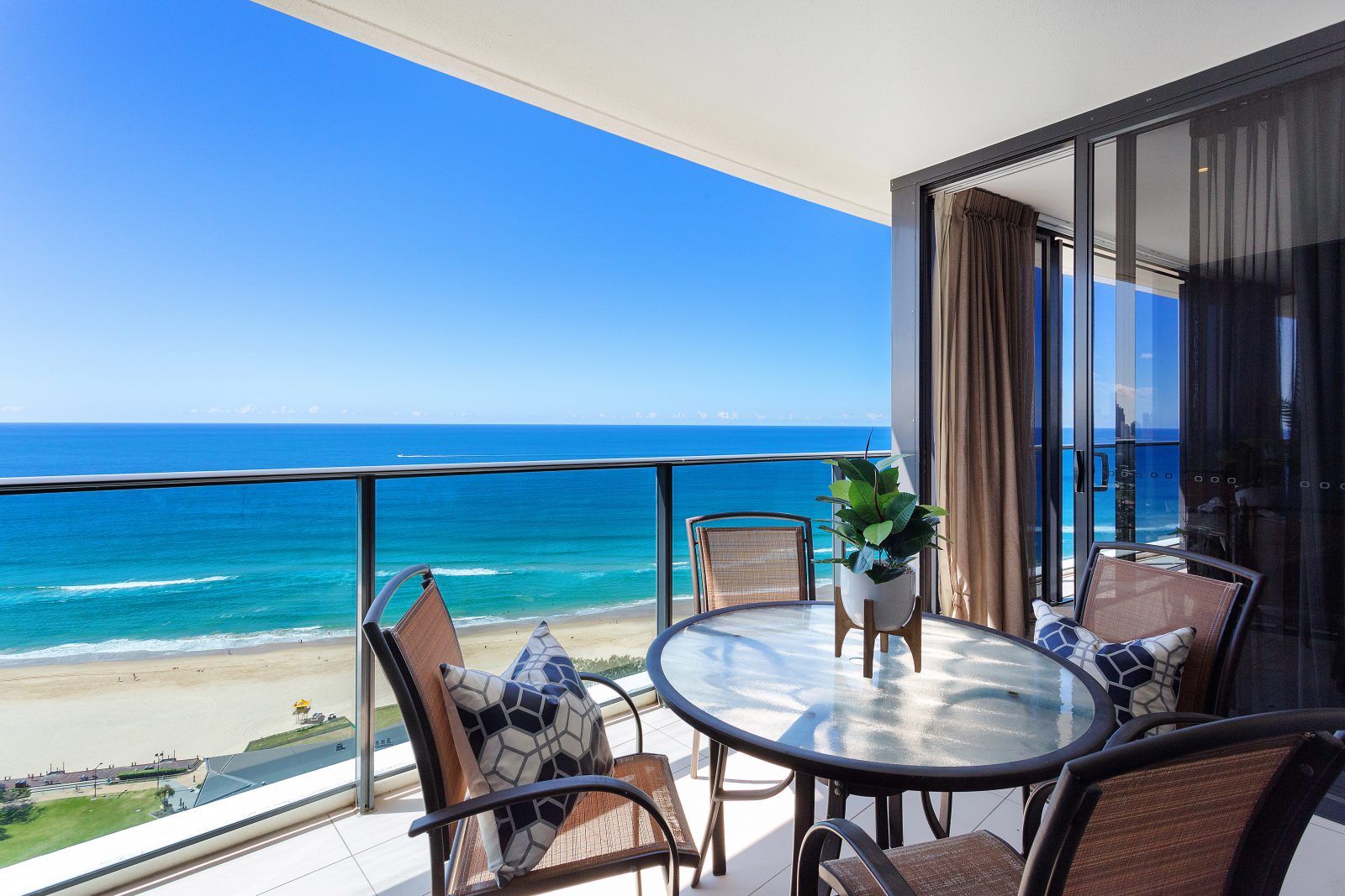 A balcony with a table and chairs overlooking the ocean.