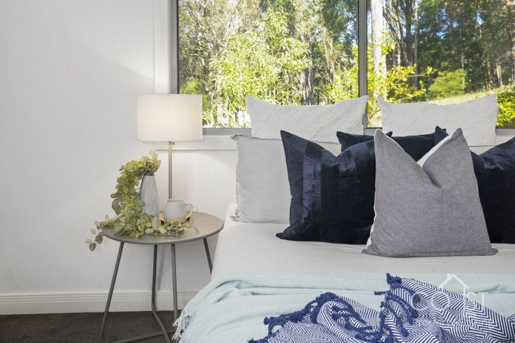 A bedroom with a bed , nightstand , lamp and window.