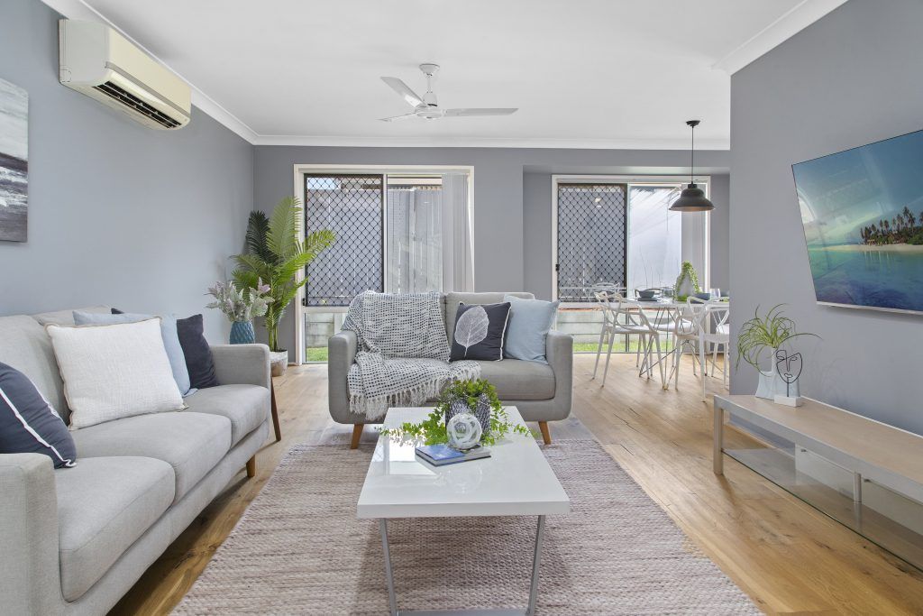 A living room with two couches , a coffee table , and a flat screen tv.