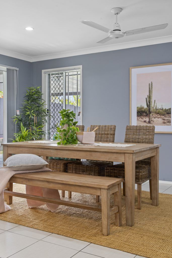 A dining room with a wooden table and benches and a ceiling fan.