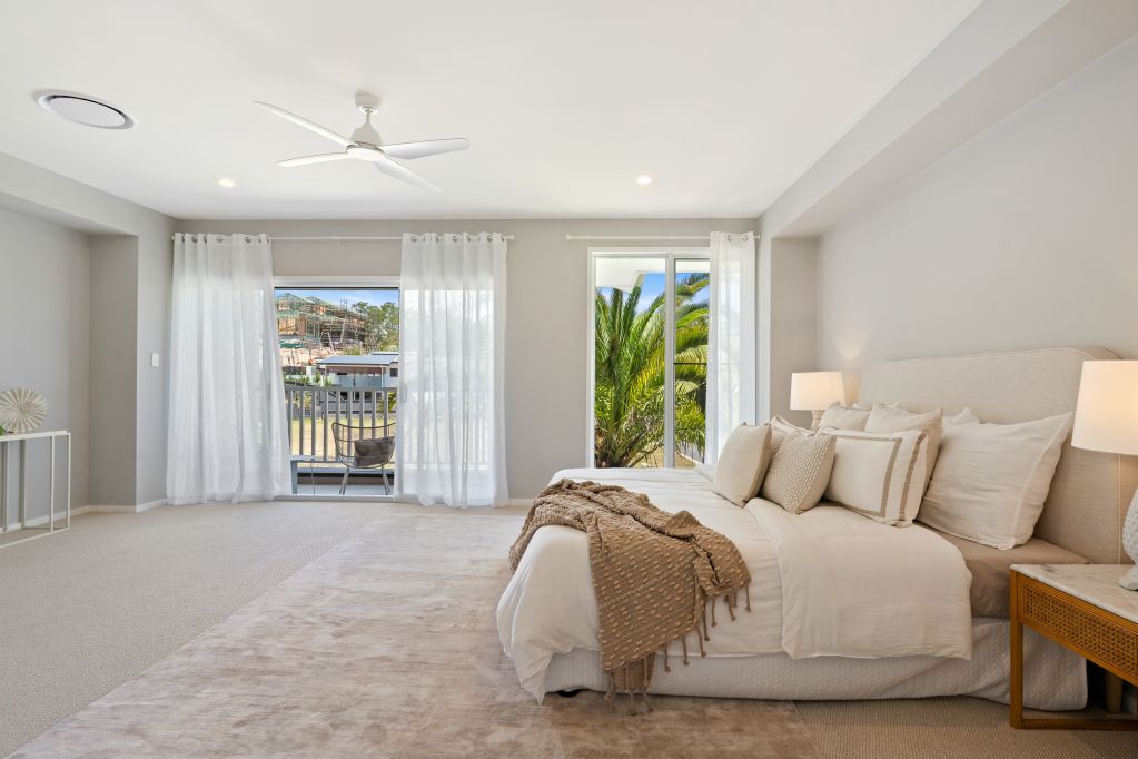 Bright modern bedroom with a large bed, white curtains, and sliding doors to a balcony.