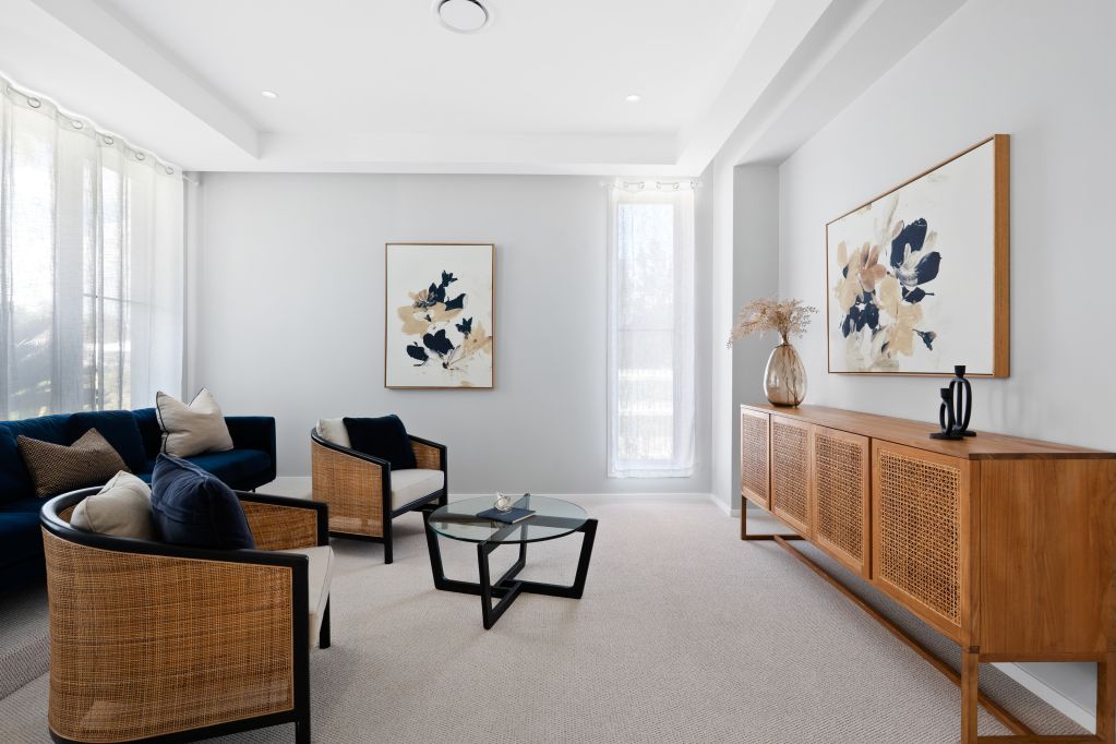 Bright living room with woven chairs, a low coffee table, and abstract wall art on white walls.