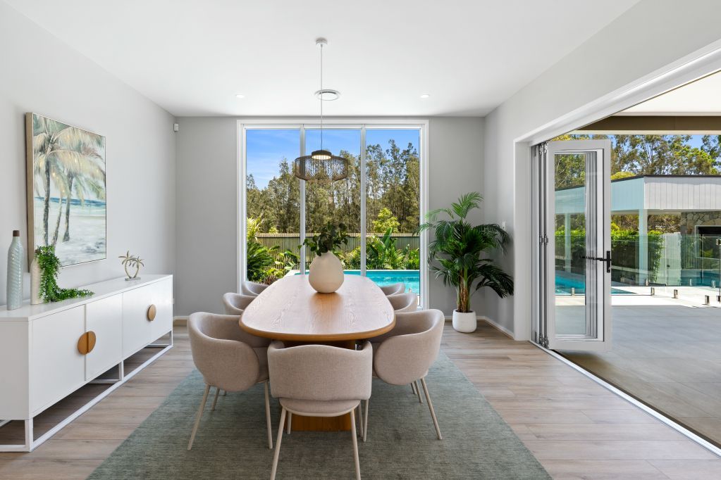 Bright dining room with round table, large windows, and sliding glass doors to a sunny patio.