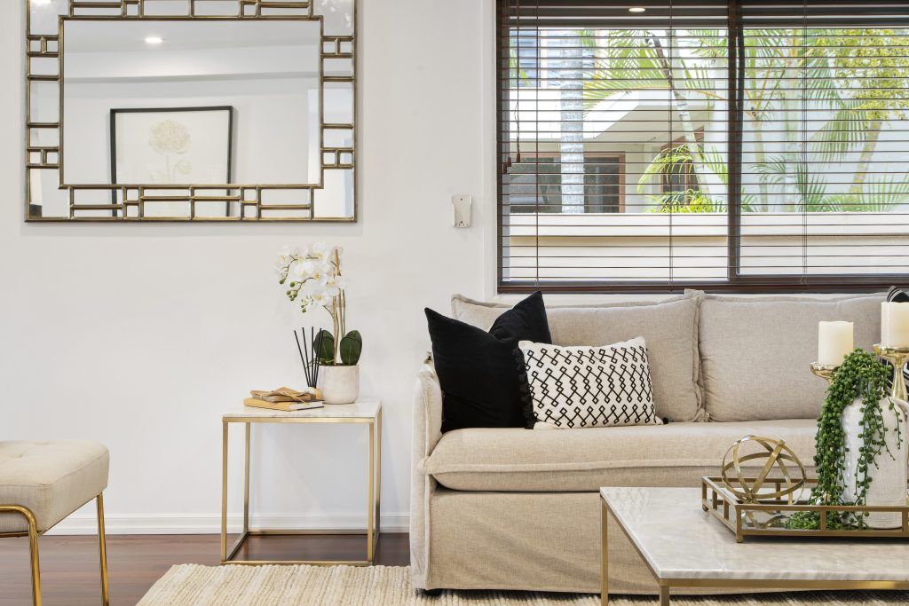 A living room with a couch , coffee table , and mirror.