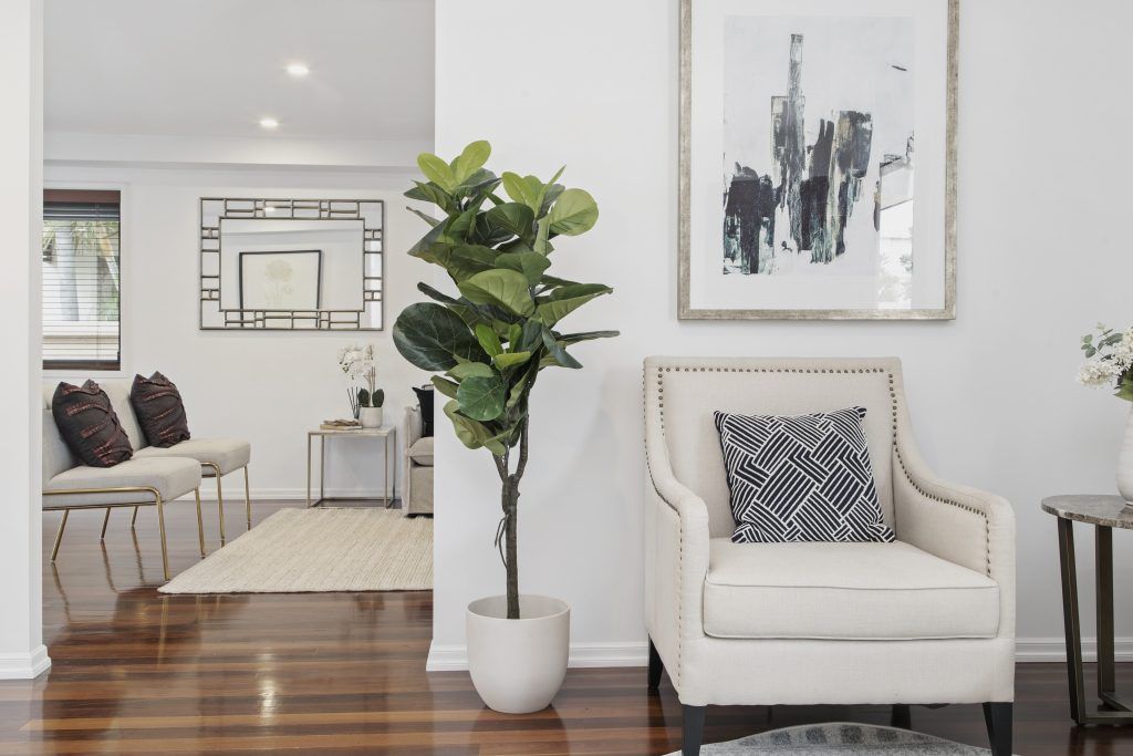 A living room with a chair and a potted plant.