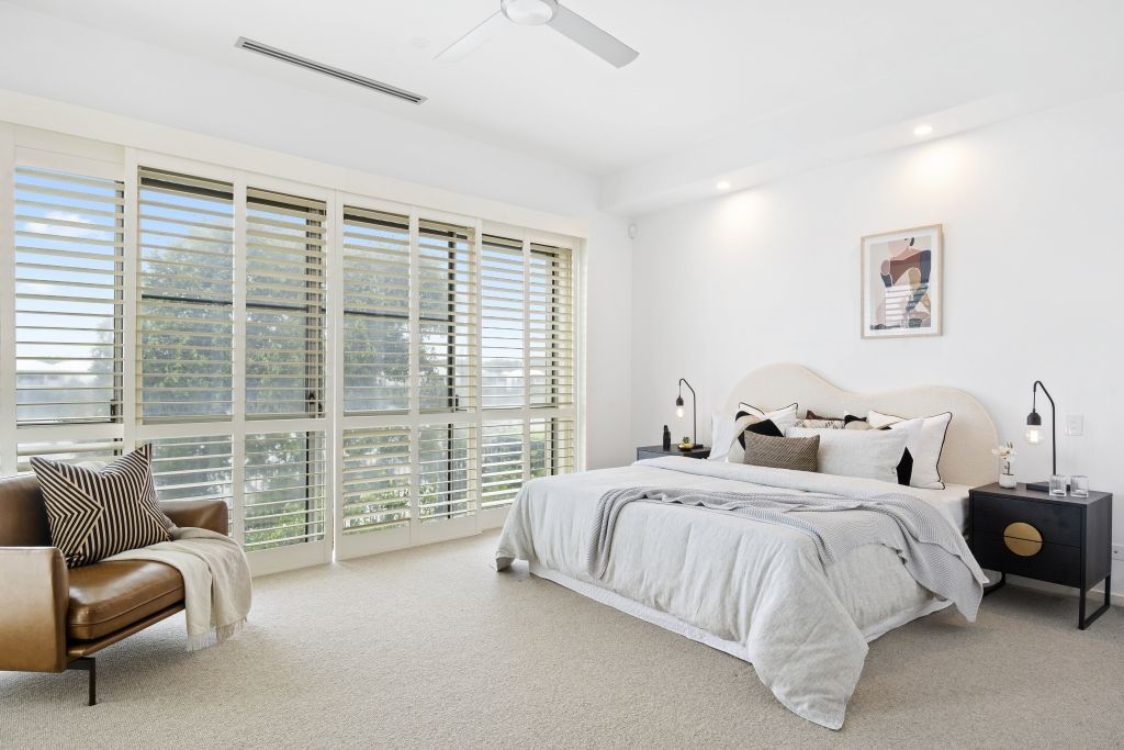 A bedroom with a large bed , a couch , and a ceiling fan.