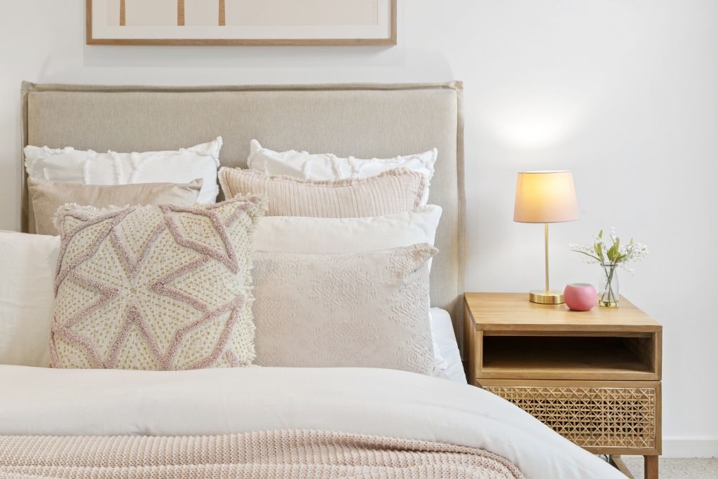 A bedroom with a bed , nightstand , lamp and painting on the wall.
