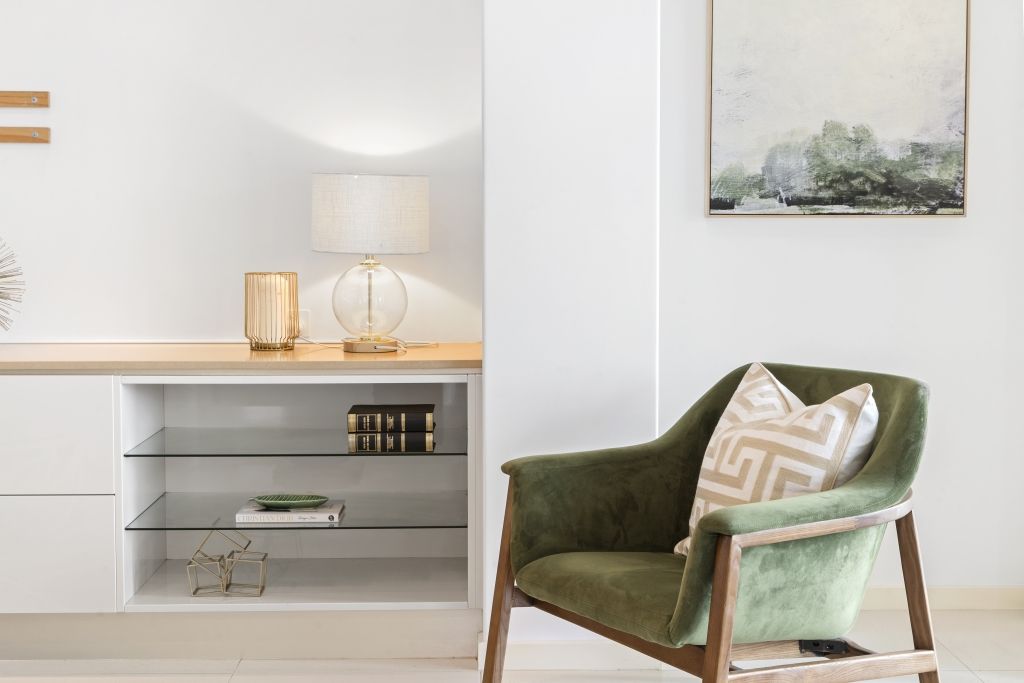 A living room with a green chair and a painting on the wall.