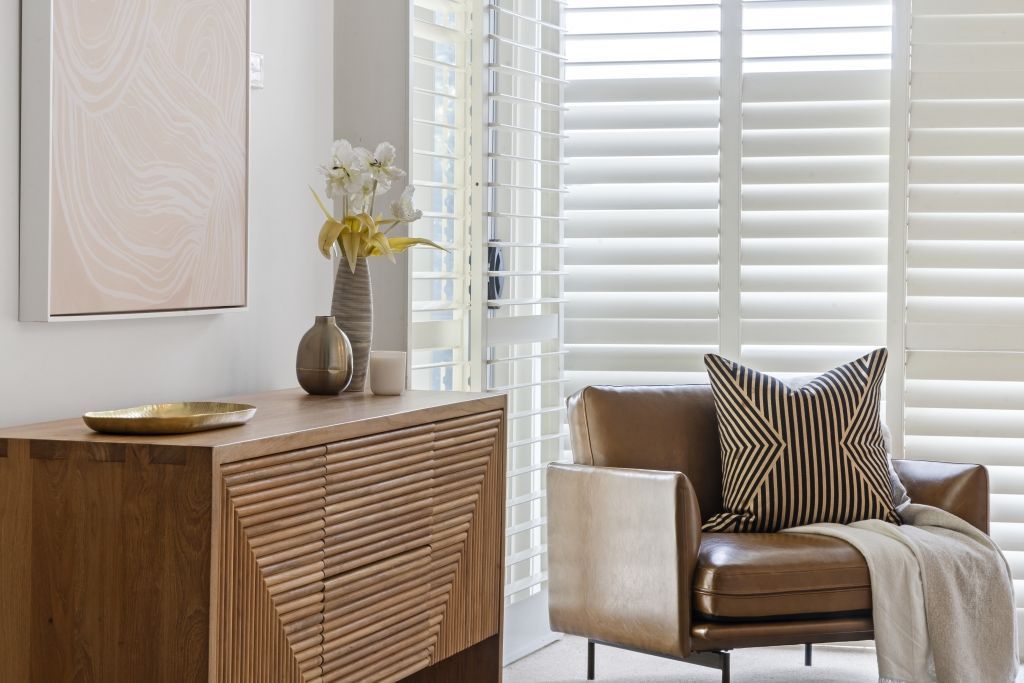 A living room with a brown leather chair and a wooden dresser.