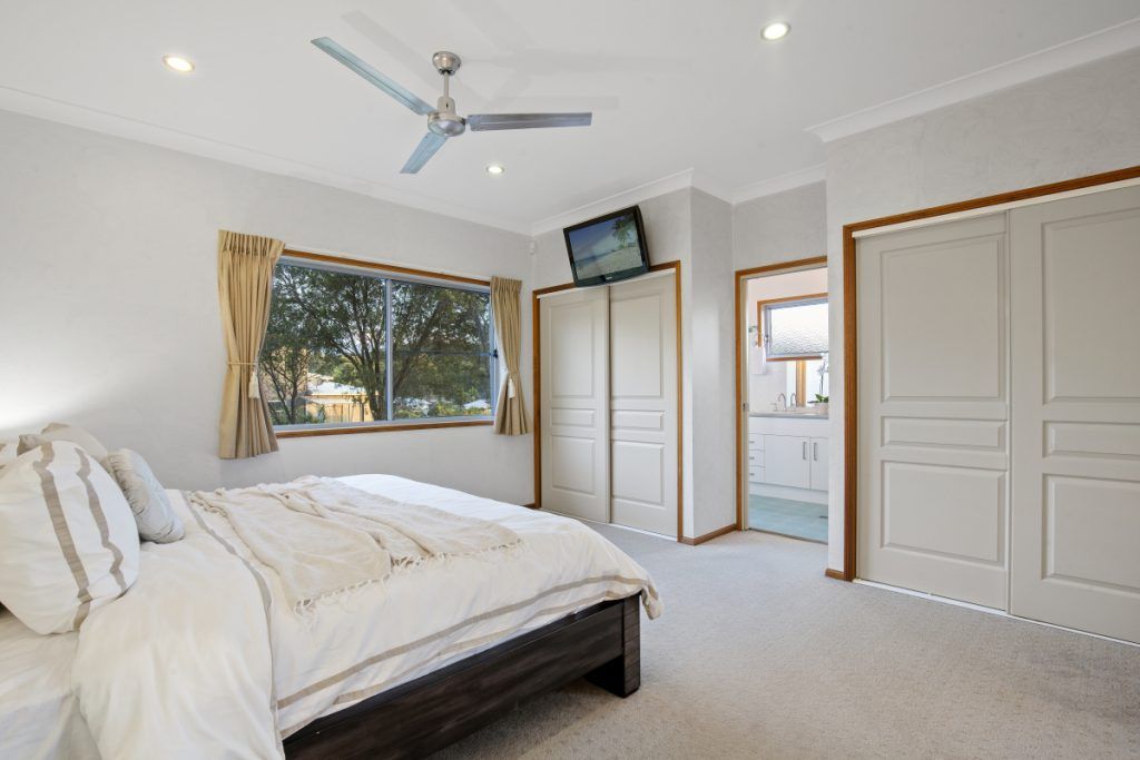 A bedroom with a large bed and a ceiling fan.