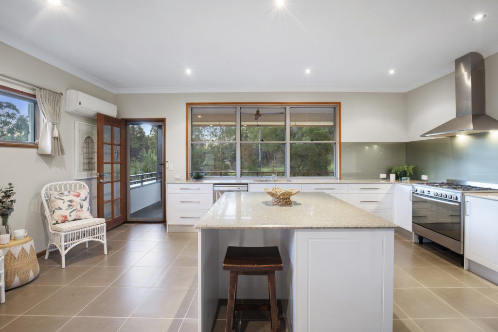 A kitchen with white cabinets , a large island , a stove and a chair.