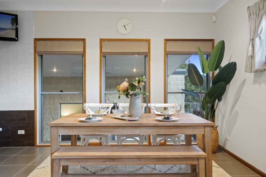 A dining room with a wooden table and benches and a clock on the wall.