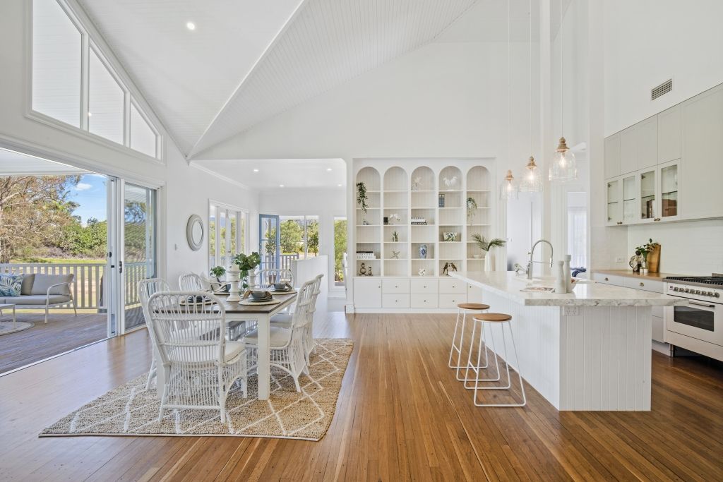 A kitchen and dining room in a house with hardwood floors and white cabinets.