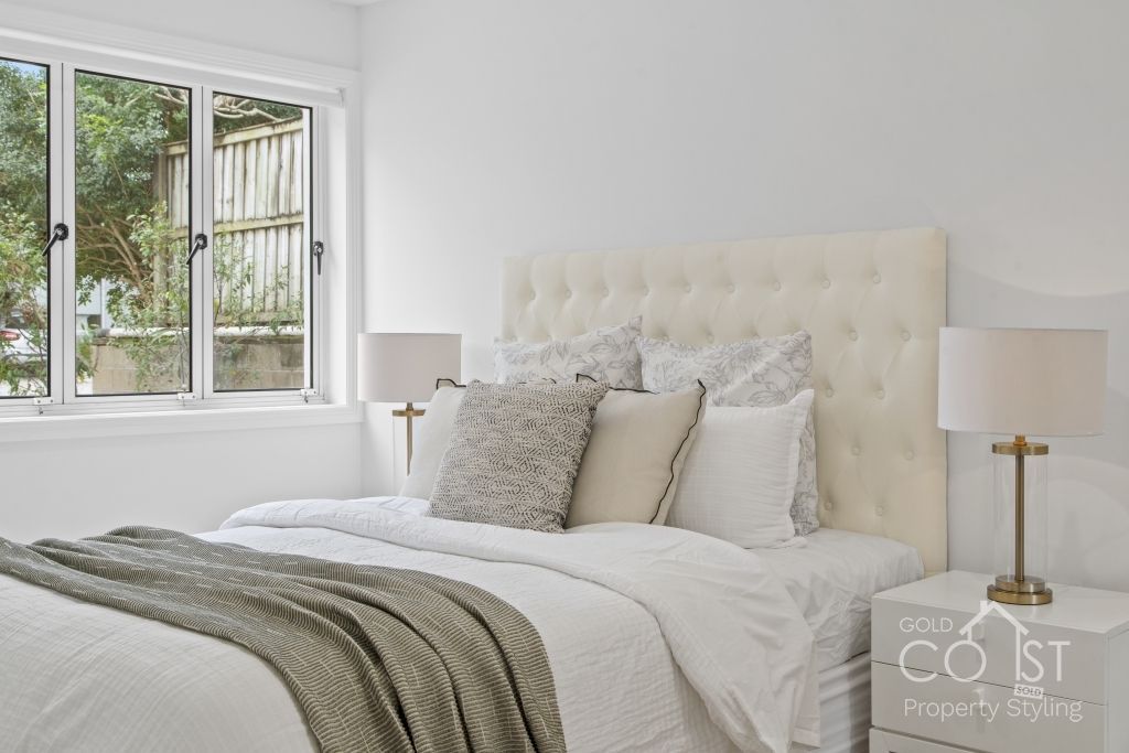 A bedroom with a bed , nightstand , lamp and window.