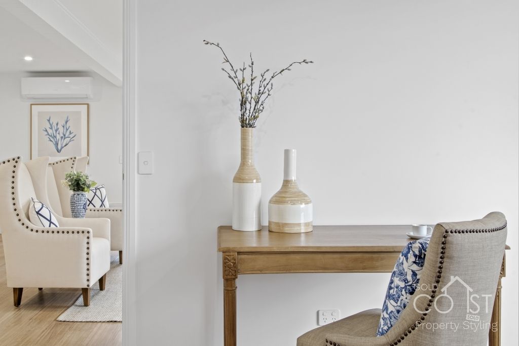 A living room with a table and chairs and a vase on the table.