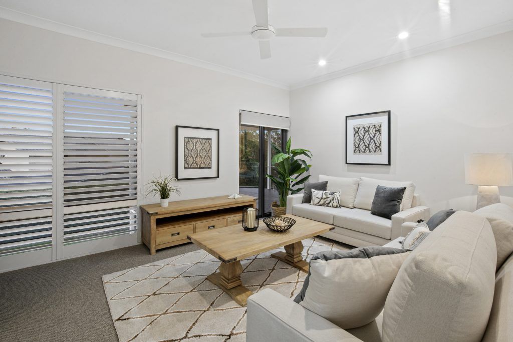 A living room with a couch , chair , coffee table and a ceiling fan.